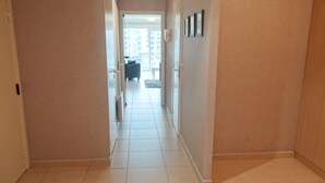 A corridor with a tiled floor leading to a room with a bed and a window. - Apartment in Nieuwpoort With Terrace (Nieuwpoort)
