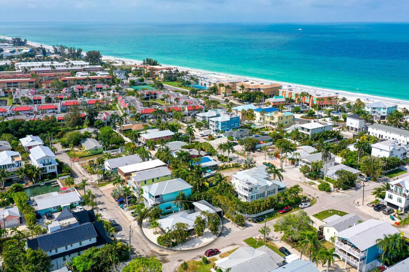 An aerial view of a coastal residential area with houses, a beach, and a clear view of the ocean.