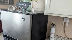 A kitchen with a stainless steel refrigerator, a granite countertop, and a water dispenser.