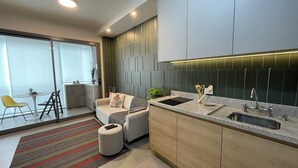 A modern kitchen with a built-in oven, a sink, and a dining area with a sofa and chairs. - Apto Próximo Oscar Freire e Rebouças (Pinheiros São Paulo)