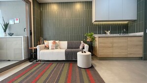 A modern living room with a sofa, a coffee table, and a kitchen area with a countertop and cabinets. - Apto Próximo Oscar Freire e Rebouças (Pinheiros São Paulo)