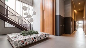 A modern lobby with a geometric-patterned reception desk, a wooden slat wall, and a staircase. - Apto Próximo Oscar Freire e Rebouças (Pinheiros São Paulo)