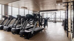A gym with treadmills, weight machines, and a large window providing a view of the city. - Apto Próximo Oscar Freire e Rebouças (Pinheiros São Paulo)