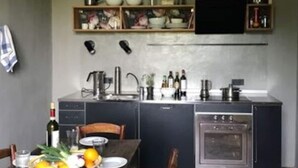 A compact kitchen with a built-in oven, a sink, and a dining area with a table set for two. - Beautiful Apartment in Tuscany (Casciana Terme Lari)