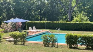 A backyard with a swimming pool, lounge chairs, and a covered seating area. - Beautiful Apartment in Tuscany (Casciana Terme Lari)
