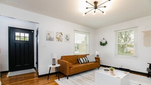 A modern living room with a brown sofa, white coffee table, and a black door.
