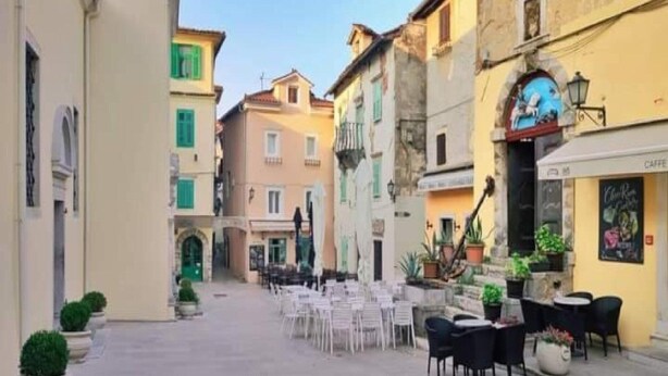 A narrow street with outdoor seating, buildings with balconies, and a café on the right. - Apartment RR - One Bedroom Apartment With Balcony (Lovran)