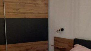 A bedroom with a wooden headboard, a bed with a pink pillow, and a mirror with a wooden frame. - Apartment RR - One Bedroom Apartment With Balcony (Lovran)