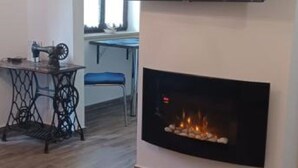 A modern living room with a flat-screen TV mounted above a fireplace. - Apartment RR - One Bedroom Apartment With Balcony (Lovran)