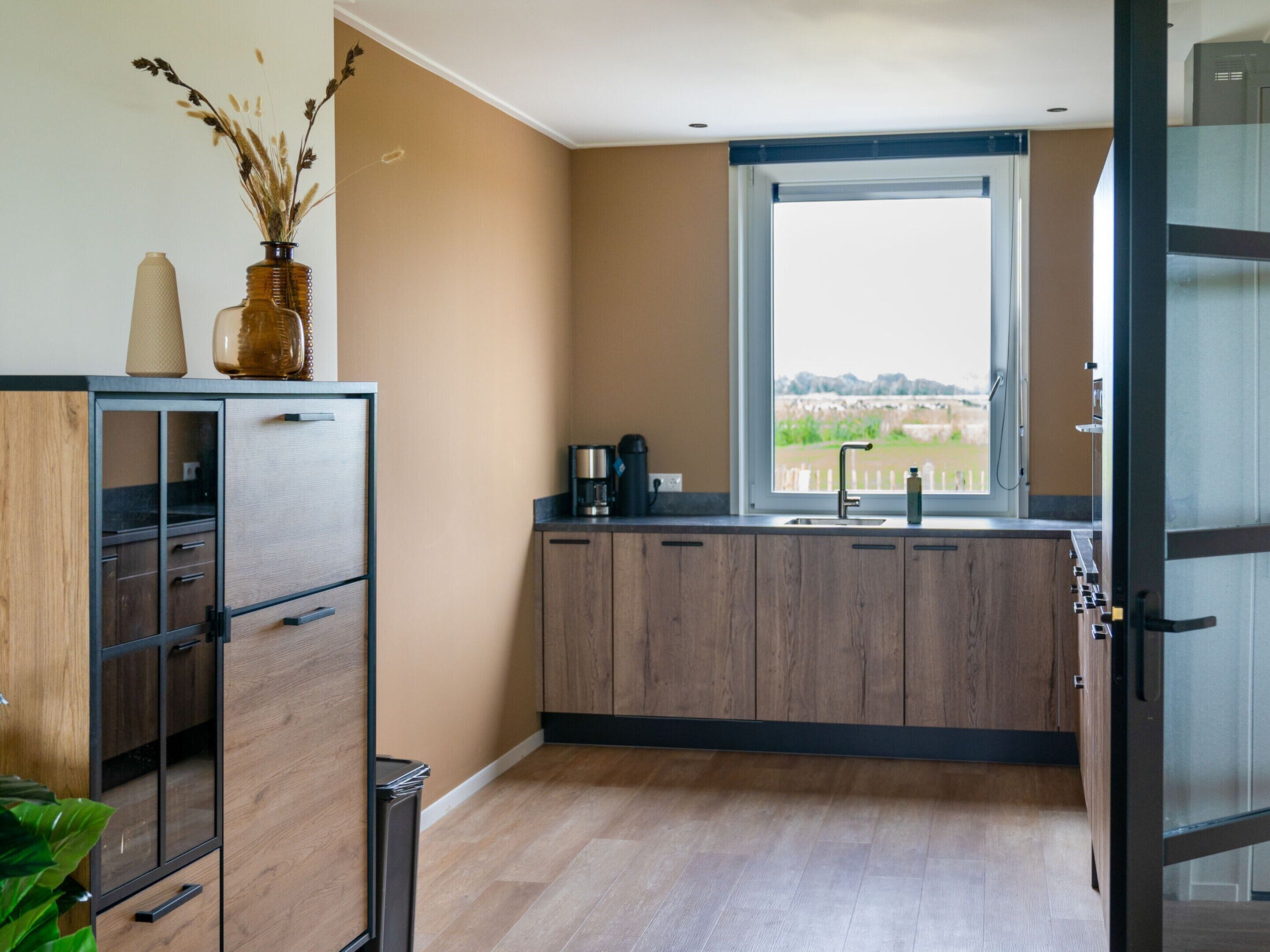 Une cuisine moderne avec des meubles en bois, un four encastré et une fenêtre donnant sur un paysage pittoresque.