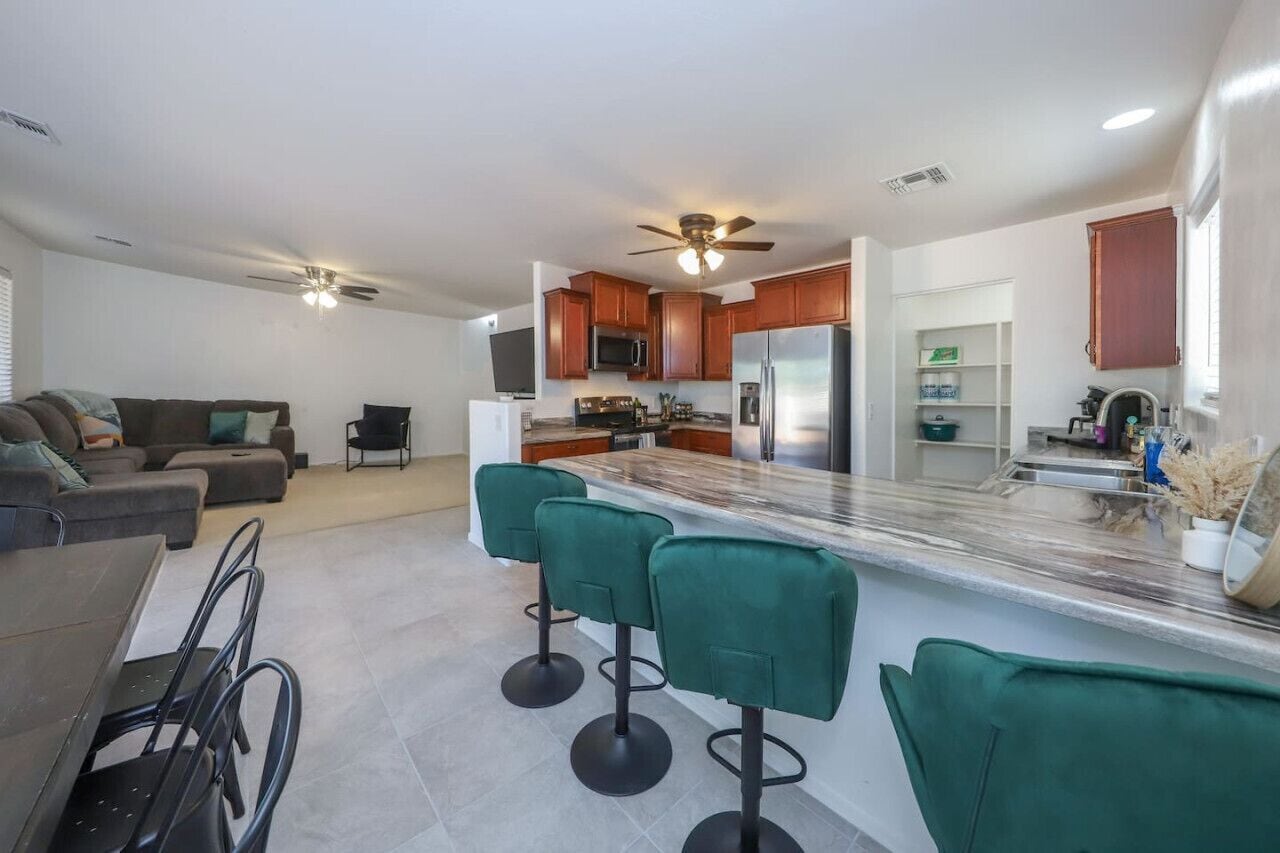 A modern kitchen with a central island, bar stools, and a dining area with a table and chairs.