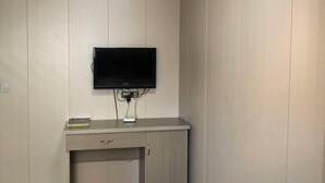 A room with a flat-screen TV mounted on the wall, a desk with a drawer, and a small book on the desk. - Cangnan Water View Hotel (Cangnan)