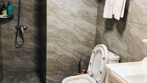 A bathroom with a toilet, a shower area, and a towel rack. - Cangnan Water View Hotel (Cangnan)