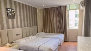 A hotel room with two beds, a nightstand, a window with curtains, and a wall-mounted air conditioner. - Cangnan Water View Hotel (Cangnan)