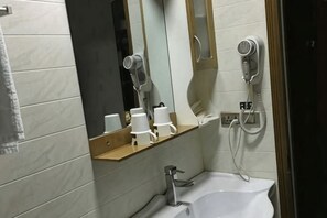 A bathroom with a sink, mirror, hairdryer, and cup holders. - Cangnan Water View Hotel (Cangnan)