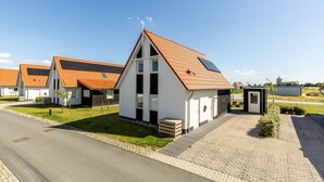 A row of modern houses with orange tiled roofs, a paved driveway, and a small garden area. - Holiday Home in Scherpenisse Near Oosterschelde (Scherpenisse)