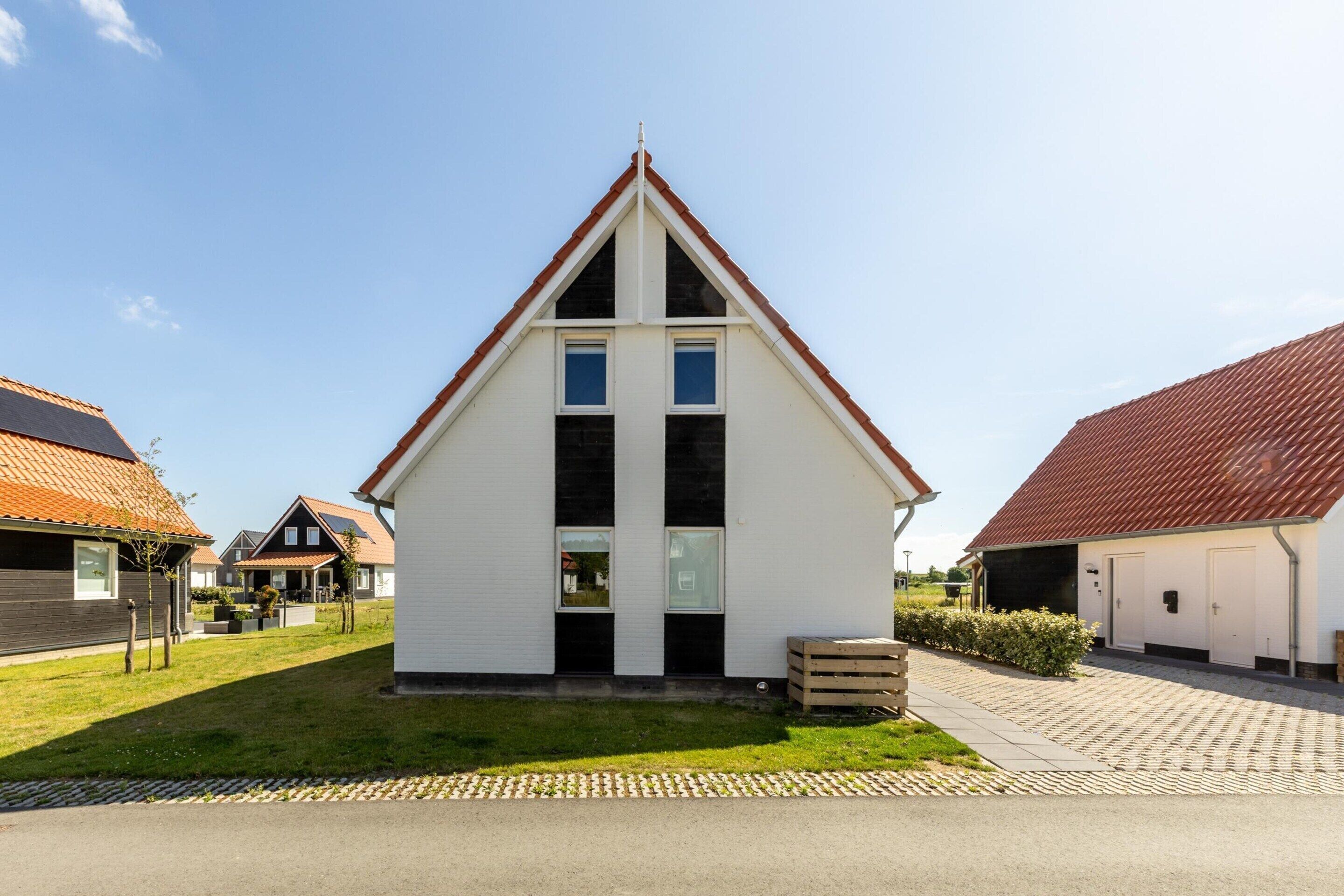 A modern house with a triangular roof, a front porch, and a small front yard.
