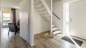 A modern interior with a wooden floor, a white staircase, a door, and a chair. - Holiday Home in Scherpenisse Near Oosterschelde (Scherpenisse)