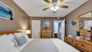 Une chambre à coucher avec un lit, un ventilateur de plafond, une commode et un miroir.