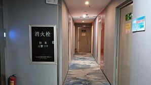 A hotel hallway with a fire extinguisher, a fire safety sign, and directional signs. - Shankee Chain Hotel (Guangzhou North Station Huacheng Road Subway Station) (Guangzhou)