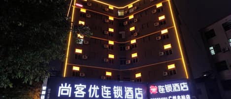 Un hotel de varios pisos con señalización iluminada y una entrada visible.