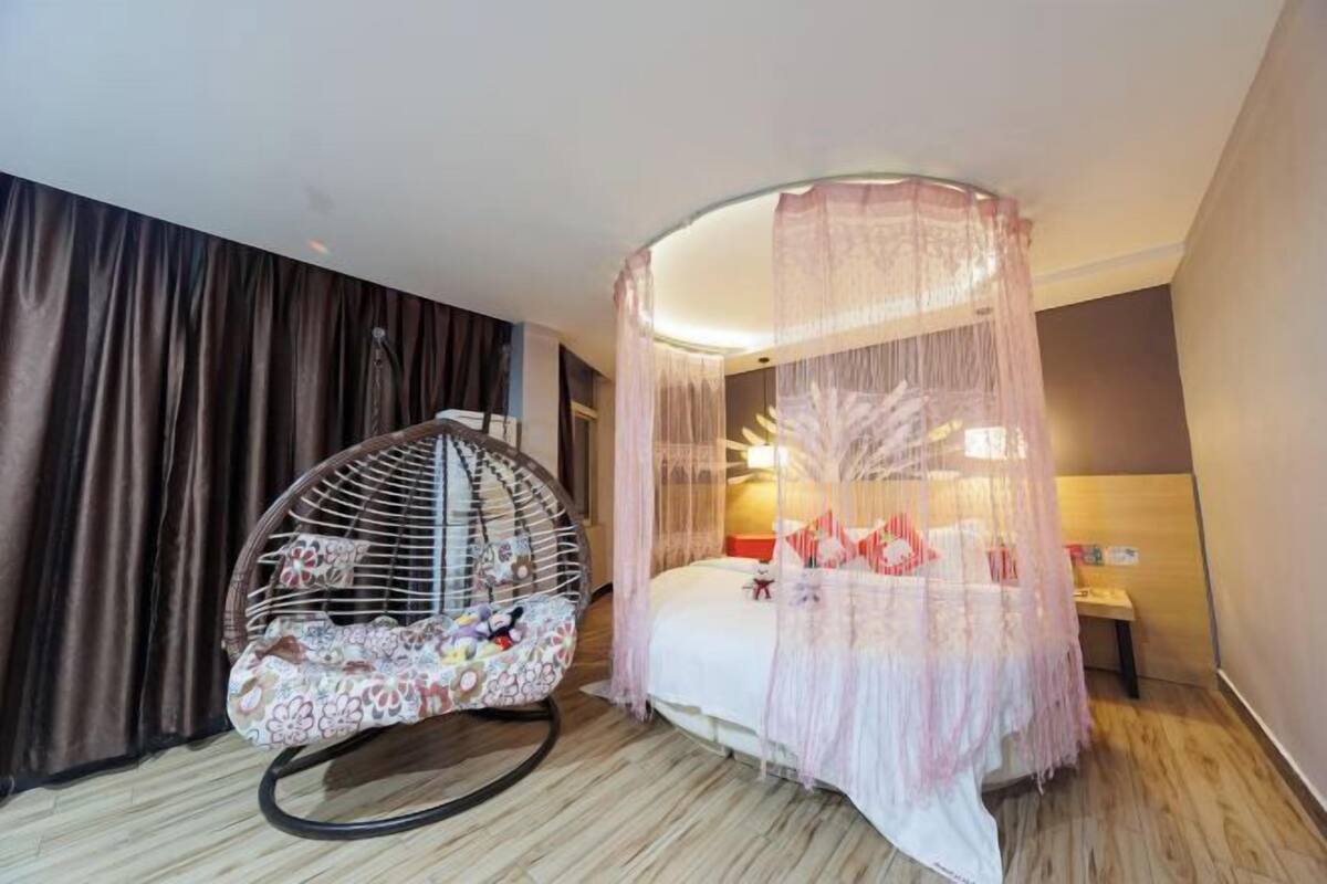A room with a bed, a hanging chair, and a canopy bed.