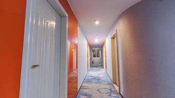 Un corridoio di un hotel con pavimento rivestito di moquette, una porta bianca a sinistra e una porta di legno a destra.