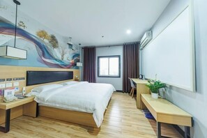 Ein Hotelzimmer mit Bett, Schreibtisch und Wandgemälde.