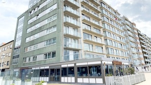 A multi-story residential building with balconies, large windows, and a ground-level commercial space. - Apartment in Nieuwpoort With Ocean Views (Nieuwpoort)