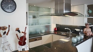 A modern kitchen with a glass island, stainless steel appliances, and decorative items. - Apartment in Nieuwpoort With Ocean Views (Nieuwpoort)