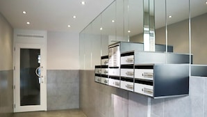 A modern elevator with a glass door, a wall-mounted storage unit with multiple drawers, and a tiled floor. - Apartment in Nieuwpoort Near the Beach (Nieuwpoort)