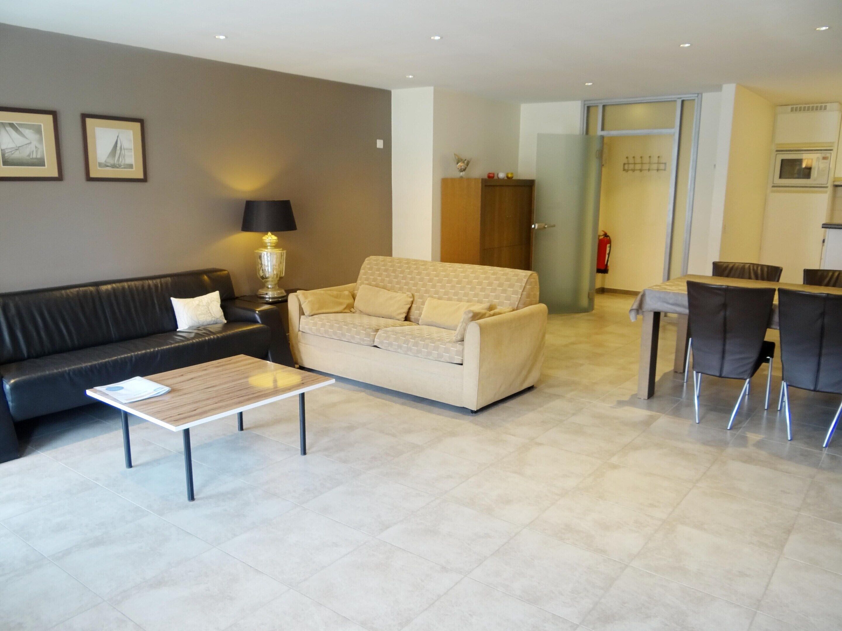 A living room with a sofa, a coffee table, and a dining area with chairs.