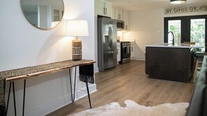 A modern kitchen with a central island, stainless steel appliances, and a hanging light fixture. - With GOLF CART! 1 mile ride to the beach & Downtown Ocean Springs! Clark Cottage (Ocean Springs)