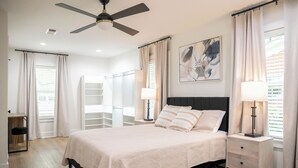 A bedroom with a bed, bedside tables, a ceiling fan, a desk, and a chair. - With GOLF CART! 1 mile ride to the beach & Downtown Ocean Springs! Clark Cottage (Ocean Springs)