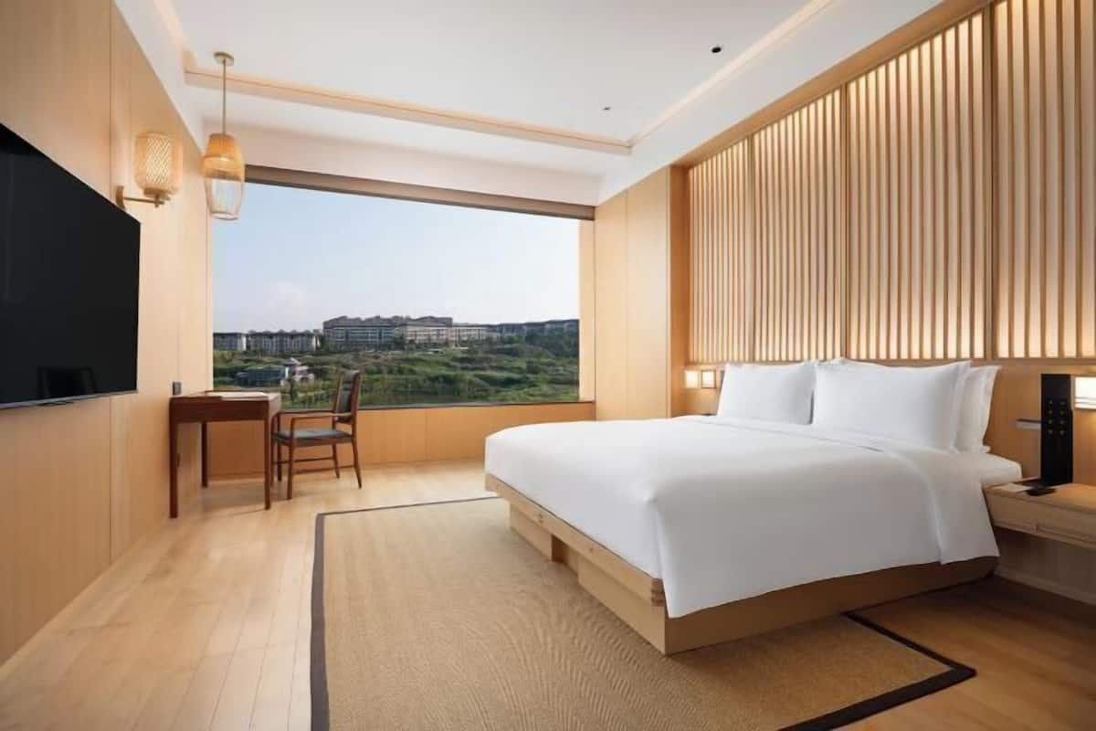 A modern hotel room with a large bed, a desk, and a chair.