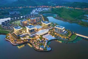 A modern waterfront property with multiple buildings, a marina, and a bridge connecting to the mainland. - New World Chongqing Hotel (Chongqing)