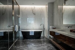 A modern bathroom with a freestanding bathtub, a glass shower enclosure, and a vanity with a mirror.