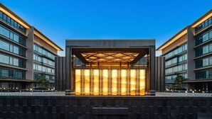 En moderne bygning med en central glasfacade og et geometrisk mønster over taget.