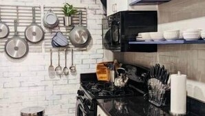 A kitchen with a black stove, hanging pots, and a microwave. - Downtown/Midtown "Family ATL CityScape" (Atlanta)