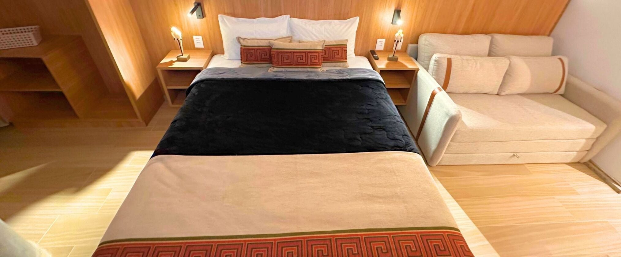 Ein Hotelzimmer mit einem Bett, Nachttischen, einer Couch und Holzboden.