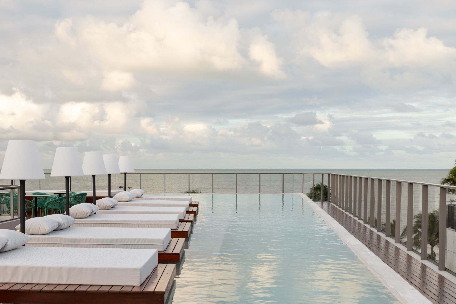 A rooftop infinity pool with lounge chairs and a view of the ocean.