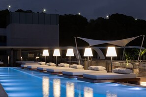 A poolside area with lounge chairs and umbrellas, a pool, and a building in the background. - AX Setai Yacht (João Pessoa)