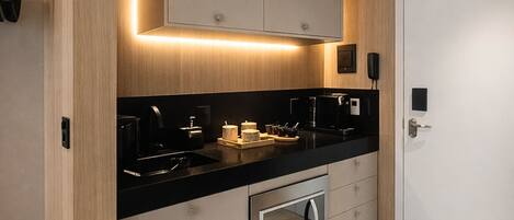 A modern kitchen with a black countertop, stainless steel appliances, and wooden cabinetry.