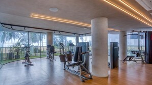 A gym with exercise equipment, large windows, and a view of palm trees. - AX Setai Yacht (João Pessoa)