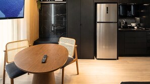 Una cocina moderna con refrigerador empotrado, un área de comedor con una mesa redonda y dos sillas, y un ventanal con vista al mar.