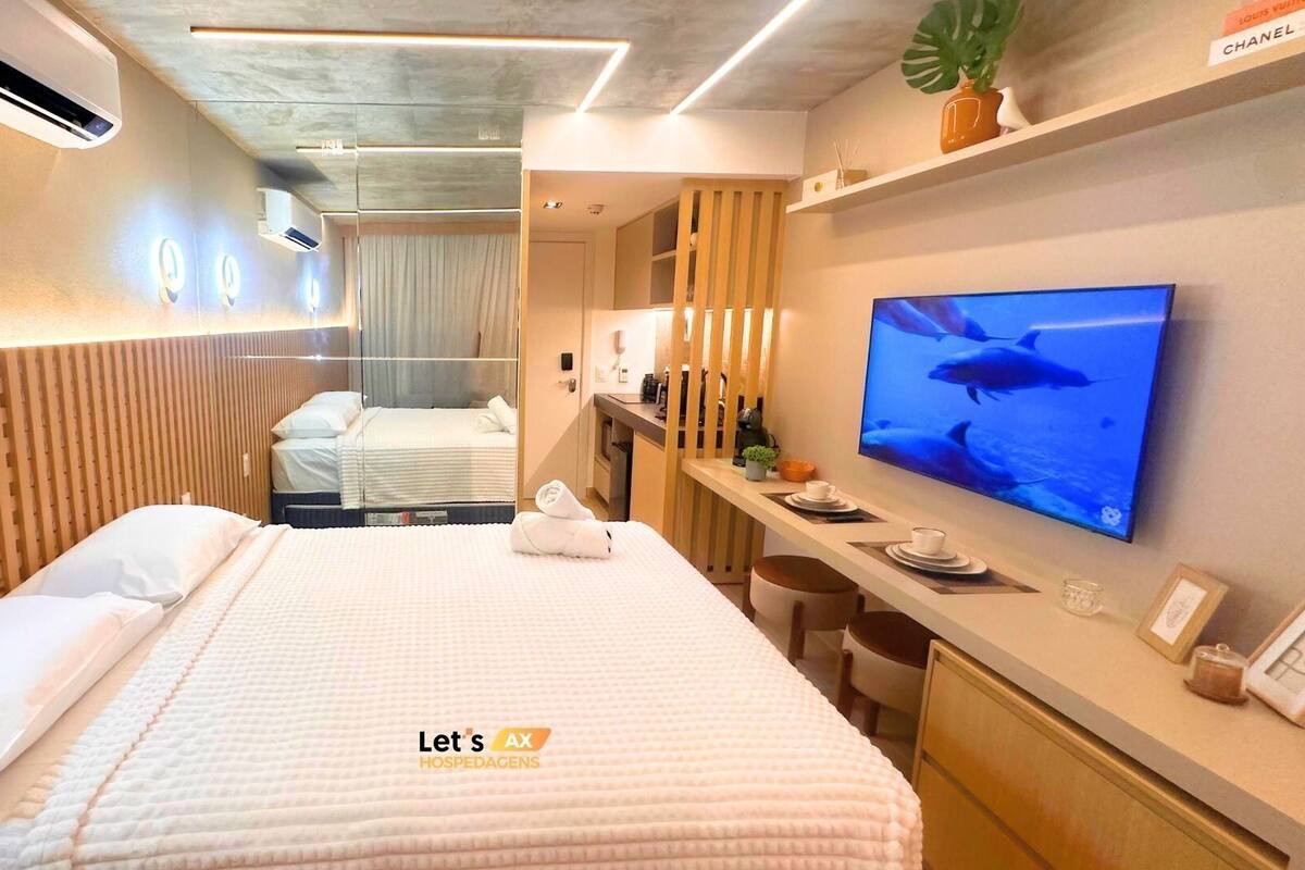 A hotel room with a bed, a TV, a desk with a chair, and a mirror.