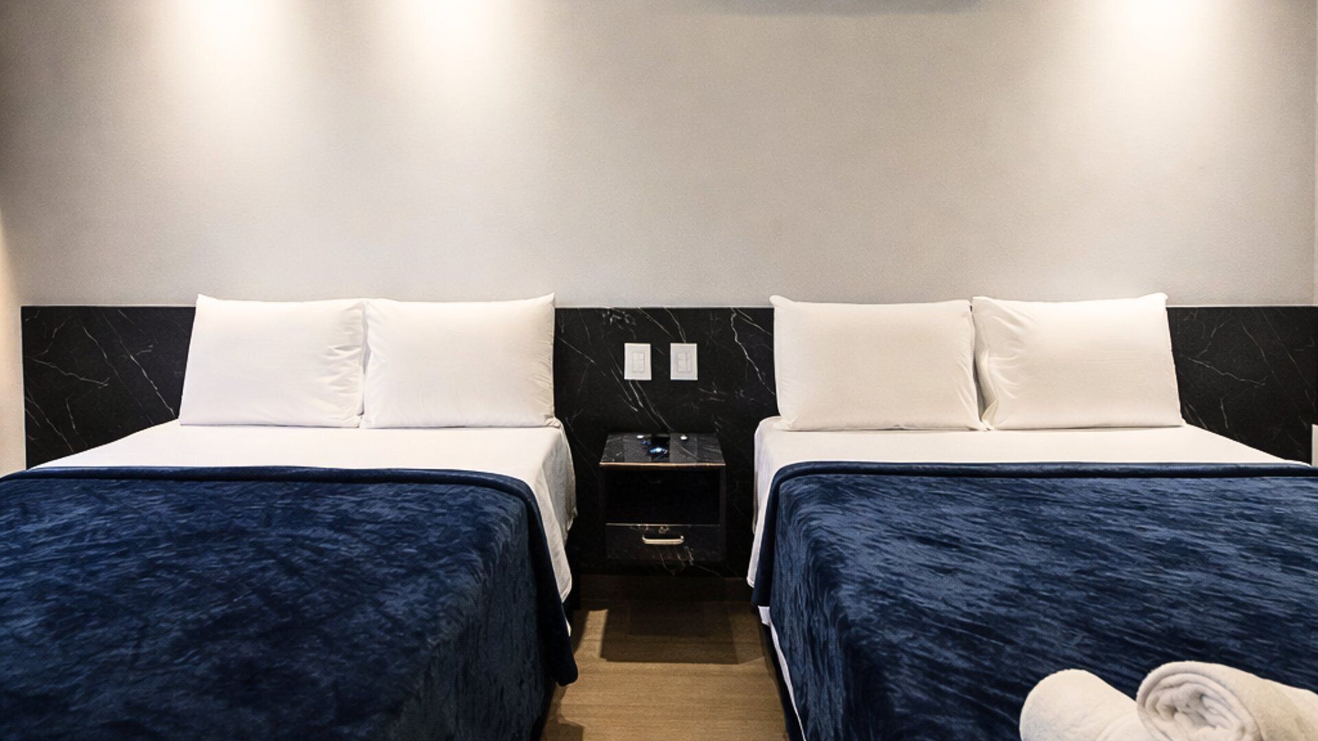 A hotel room with two beds, a nightstand, and a robe.