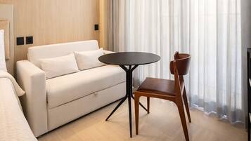 Ein modernes Hotelzimmer mit einer Couch, einem runden Tisch und einem Holzsessel.