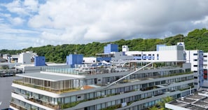 Um hotel moderno com vários andares, janelas amplas e um terraço no telhado.