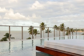 A poolside area with a view of the ocean and palm trees.